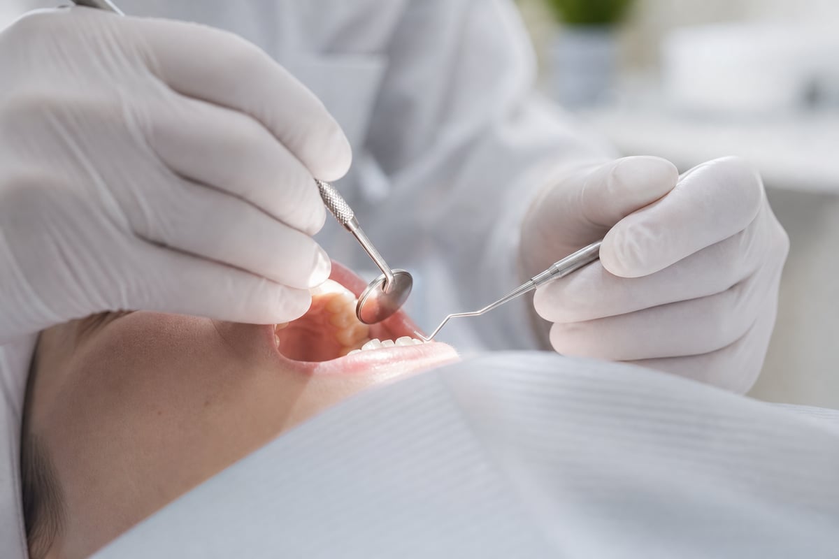 A dentist's gloved hands mid-procedure under the operatory light